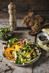 Gebratene Kürbisscheiben auf buntem Herbstsalat.
