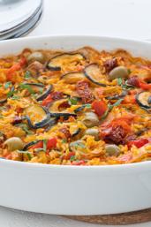 Vegane Paella mit Tomaten, Oliven und Zucchini.