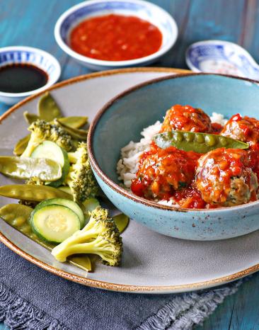 Asia-Hackbällchen süßsauer in einer Schale angerichtet auf einem Teller.