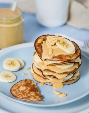 Bananen-Pancakes mit Erdnussbutter gestapelt auf einem Teller 