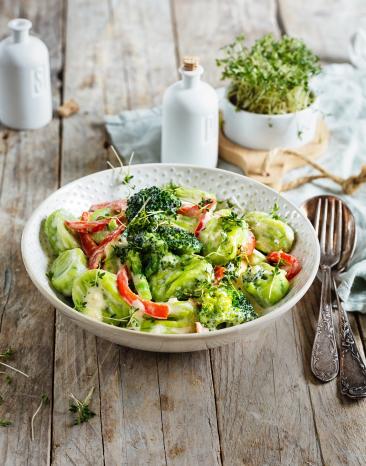 Basilikum-Gnocchi in Käsesauce auf einem Teller angerichtet.