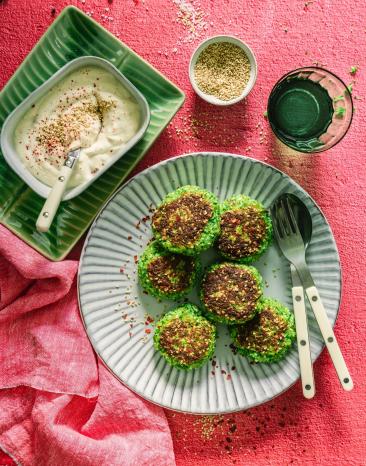 Bratlinge auf Teller verteilt mit Dip und Sesam am Tellerrand