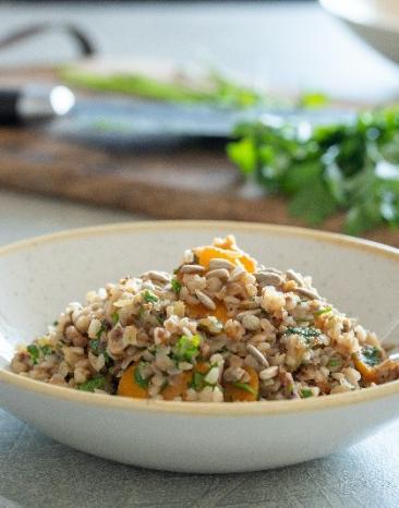 Buchweizen-Risotto mit Karotten und Sonnenblumenkernen auf einem Teller.