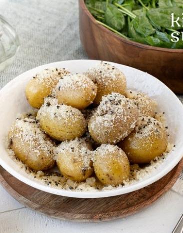 Dampfkartoffeln (Cacio e Pepe) mit Spinatsalat in zwei Schalen.
