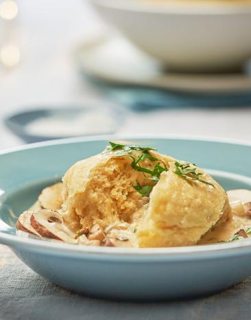 Dampfnudeln mit Pilzragout in einem Teller auf einem gedeckten Tisch.
