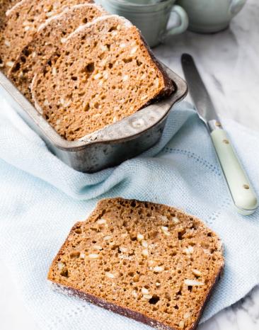 Vier Scheiben Dinkelbrot im Körbchen auf gedecktem Tisch.