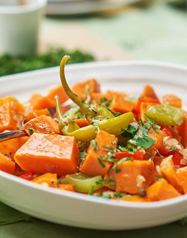 Eintopf aus Süßkartoffelwürfeln und Paprika auf Teller.