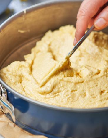 Eischwerteig wird in einer Kuchenform verstrichen.