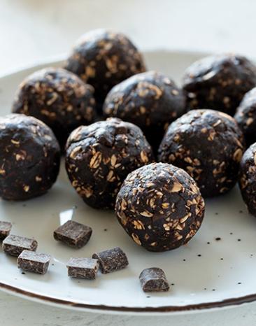 Viele Energiekugeln mit Erdnussbutter und Schokolade auf einem Teller.