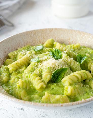 Fusilli mit Erbsen und Ricotta in einem Teller angerichtet.