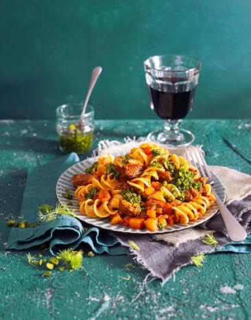 Fusilloni mit Kalbsragout und Fenchel-Pistazien-Pesto auf einem Teller angerichtet.