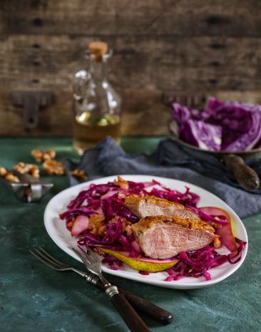 Gebratene Entenbrust mit lauwarmem Birnen-Rotkohlsalat auf einem Teller.