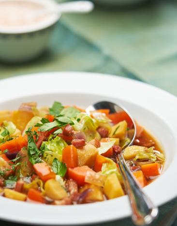 Gemüseeintopf mit Speck in einem Teller angerichtet.