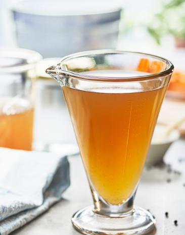 Gemüsefond in einem Messbecher.