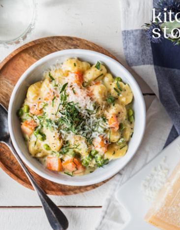 Gnocchi mit Karotten und Erbsen in einem tiefen Teller.