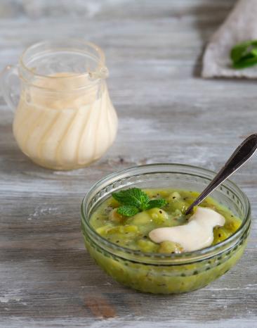 Grüne Grütze in Glasschälchen mit Löffel, Vanillesauce in Glaskännchen