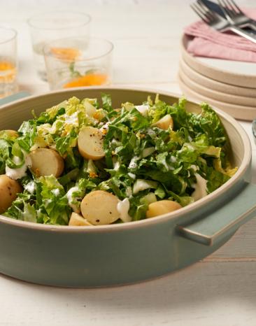 Grüner Salat mit kleinen Kartoffeln und Orangen-Sahne-Dressing in einer Schale.