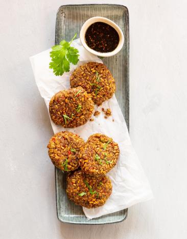 Grünkern-Rösti auf Servierteller mit Soja-Dip in kleiner Schale