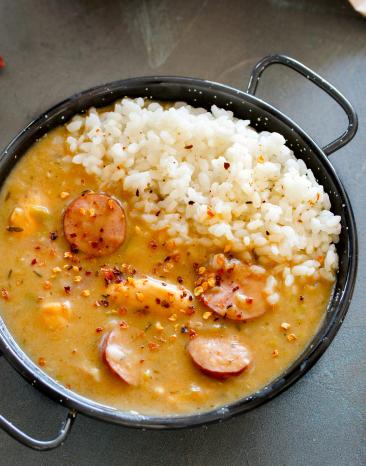 Gumbo-Eintopf mit Hähnchen und Würstchen in einer kleinen Pfanne mit Reis.