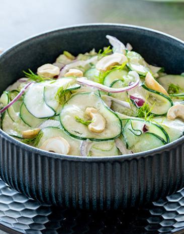 Gurkensalat mit Sellerie in einer Schüssel auf einem Tisch.