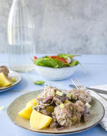 Hackbällchen Stroganoff mit Kartoffeln auf einem Teller angerichtet.
