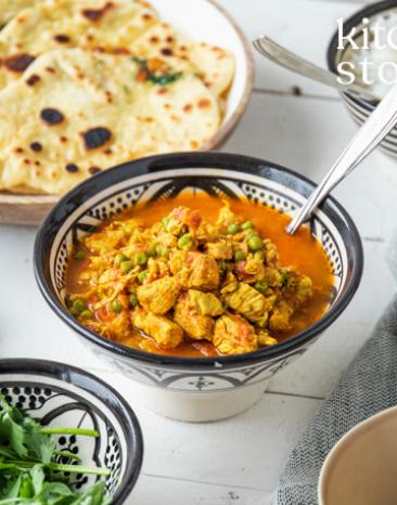 Hähnchen Tikka Masala in einer Schale, daneben Naanbrot.