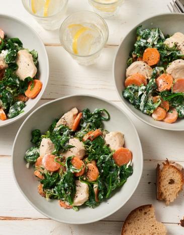 Hähnchenbrust-Medaillons mit Spinat auf drei Tellern.