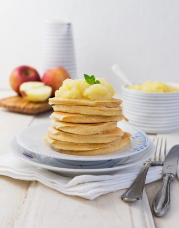 Mehrere Pancakes übereinandergestapelt mit Apfelmus obendrauf.