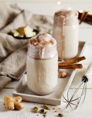 Heiße weiße Schokolade mit Kakaosahne in einem hohen Glas.