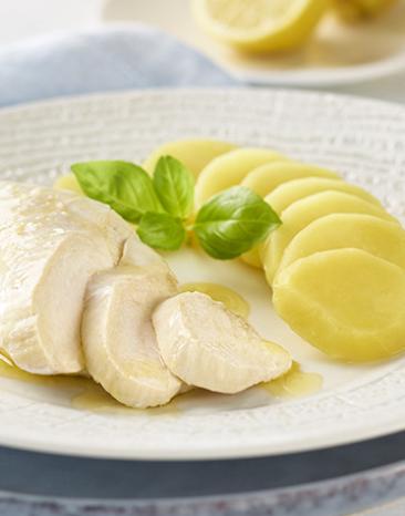 Hühnerbrust gedämpft mit Zitronenbutter und Kartoffeln auf einem Teller.