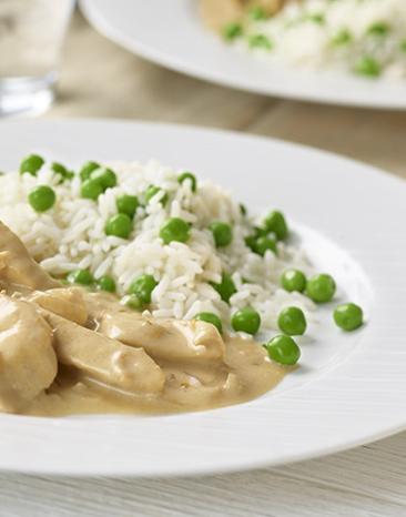 Hühnergeschnetzeltes mit Erbsenreis auf einem Teller.