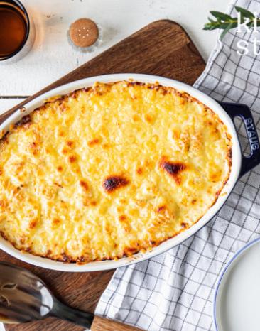 Käse-Makkaroni in einer Auflaufform auf einem Brett.