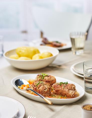 Kalbsrouladen mit Gorgonzolacreme gefüllt auf einem Teller auf einem gedeckten Tisch.