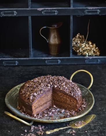 Klassische Sachertorte angeschnitten auf einer Kuchenplatte.