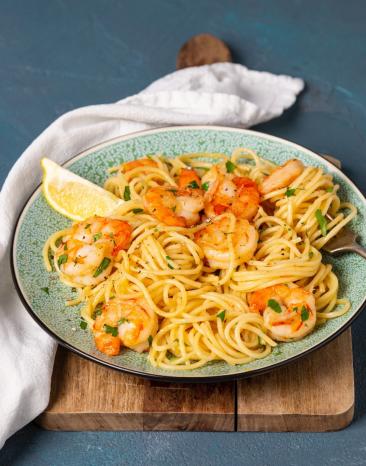 Knoblauchgarnelen in Öl mit Pasta auf einem Teller angerichtet.