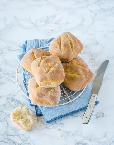 Mehrere Dinkelbrötchen aus dem Cookit mit Messer auf Marmortisch.