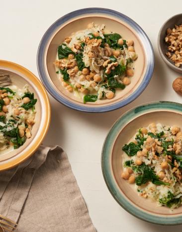Kohlrabi mit Blattspinat und Kichererbsen in drei Tellern auf einem Tisch.