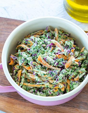 Krautsalat mit Karotten und Pesto in einem Topf auf einem Brett.