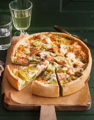 Lauchquiche mit Lachs angeschnitten auf einem Brett.