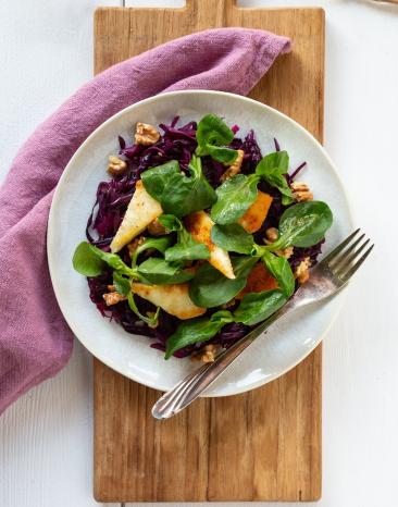 Lauwarmer Rotkohlsalat mit gebratenem Halloumi und Walnüssen in einer Schale angerichtet