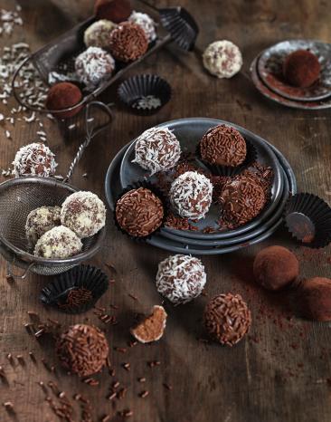 Mehrere Lebkuchenpralinen in einer Schale und daneben auf einem Tisch.