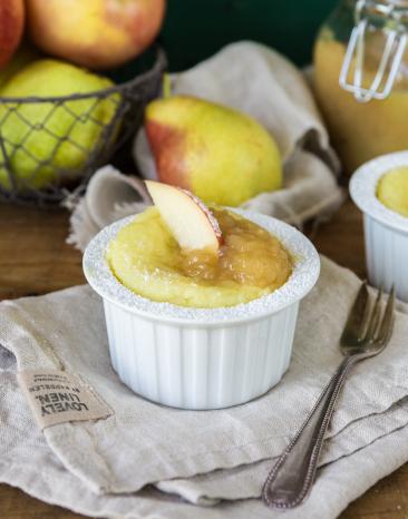 Luftiges Vanille-Soufflé mit Apfel in einem Förmchen auf einem Tisch.