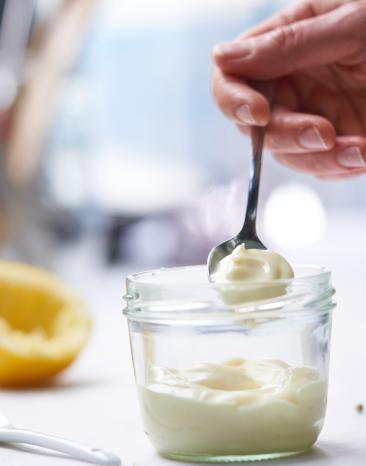 Ein Löffel Mayonnaise wird aus einem Glas genommen.