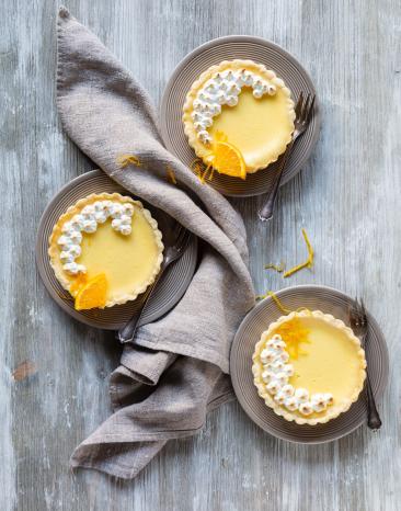 Drei Mini-Käsekuchen auf drei Tellern mit Kuchengabeln und Tuch