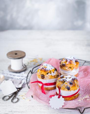 Drei Mini-Zimt-Panettone mit Puderzucker bestäubt und angerichtet.