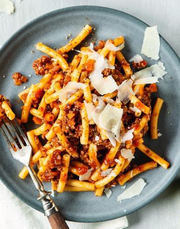 Pasta Bolognese auf Teller mit Parmesan und Basilikum garniert