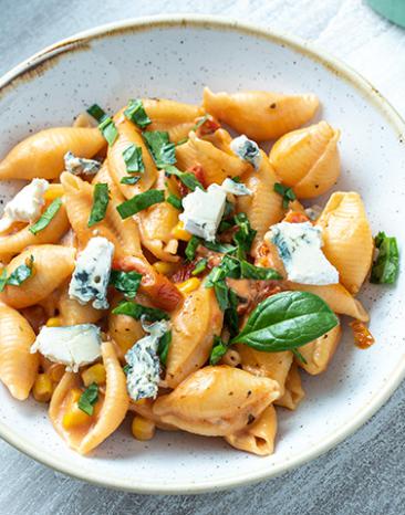 One-Pot-Pasta mit Tomaten, Mais und Blauschimmelkäse in einem Teller.