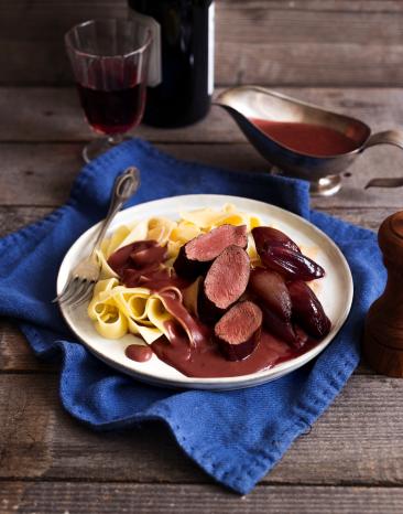 Rehfilet auf einem Nudelbett und roter Sauce.