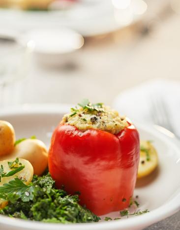 Paprikaschoten gefüllt mit Bulgur auf Blattspinat auf einem Teller.