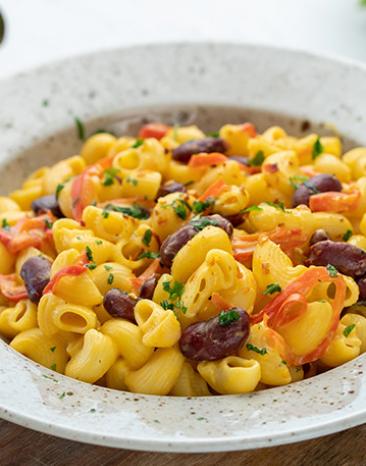 Pasta mit Bohnen, roter Paprika und Nacho-Käsesauce in einem Teller.